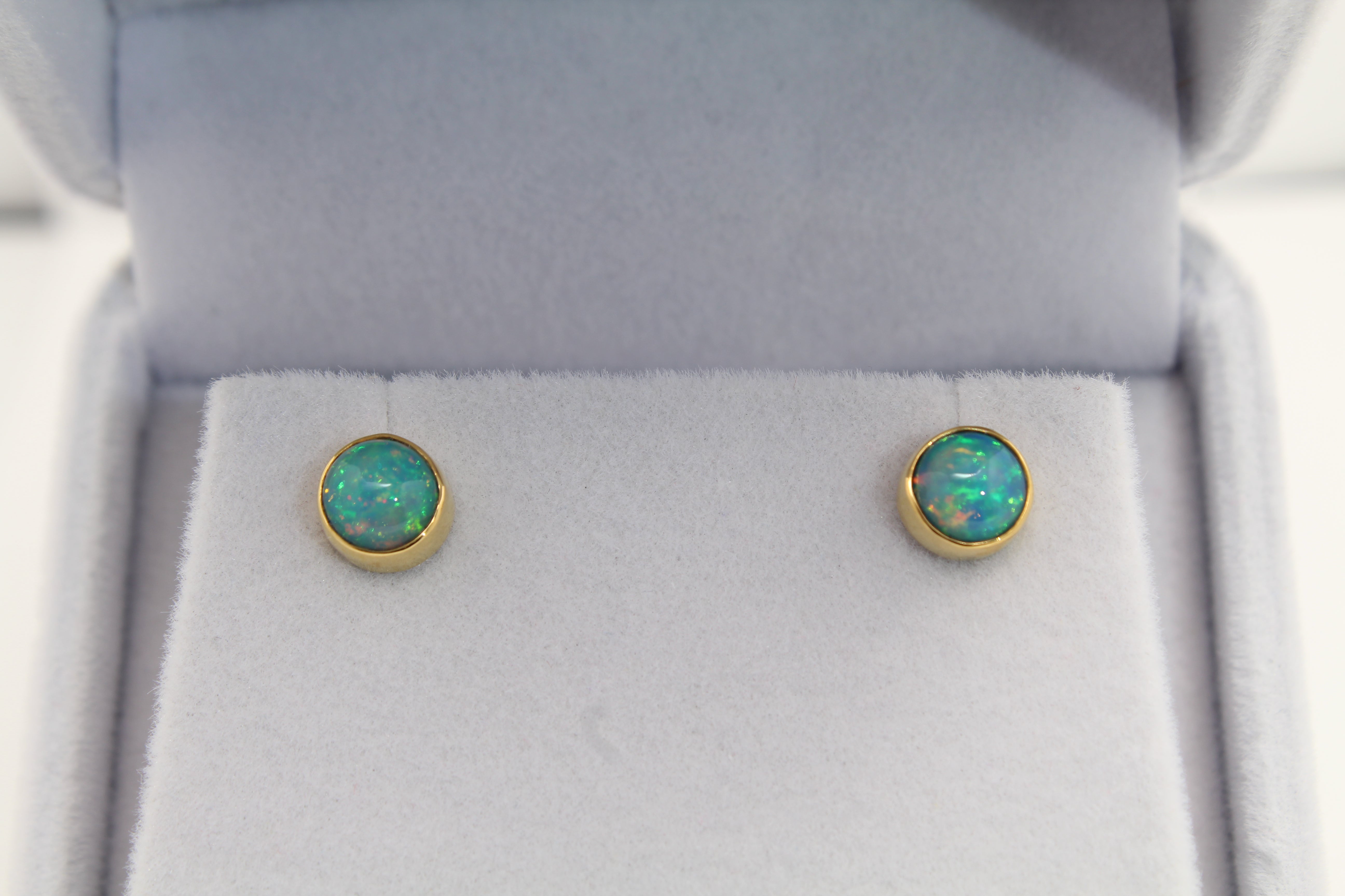 Round Ethiopian Opal stud earrings displaying vibrant blue play-of-color and green/red fire, set in 22k and 14k gold
